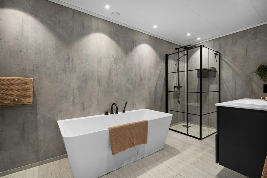 Badezimmer mit fugenlosen grauen Wänden, freistehender Badewanne und Glasdusche