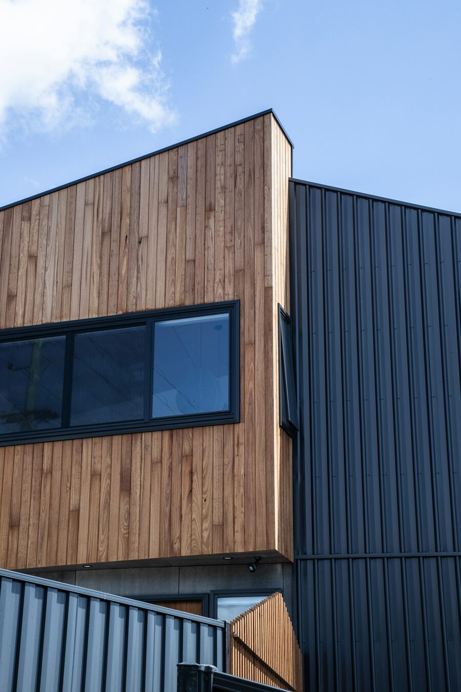 Wohnhaus mit Holzfassade aus horizontalen Brettern und dunklem Anbau