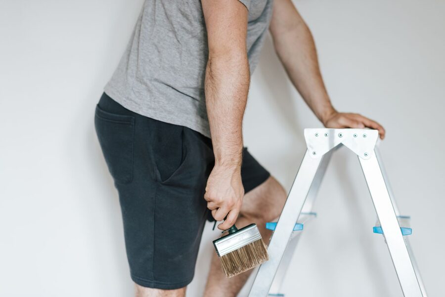 Maler auf einer Leiter mit einem Flachpinsel in der Hand